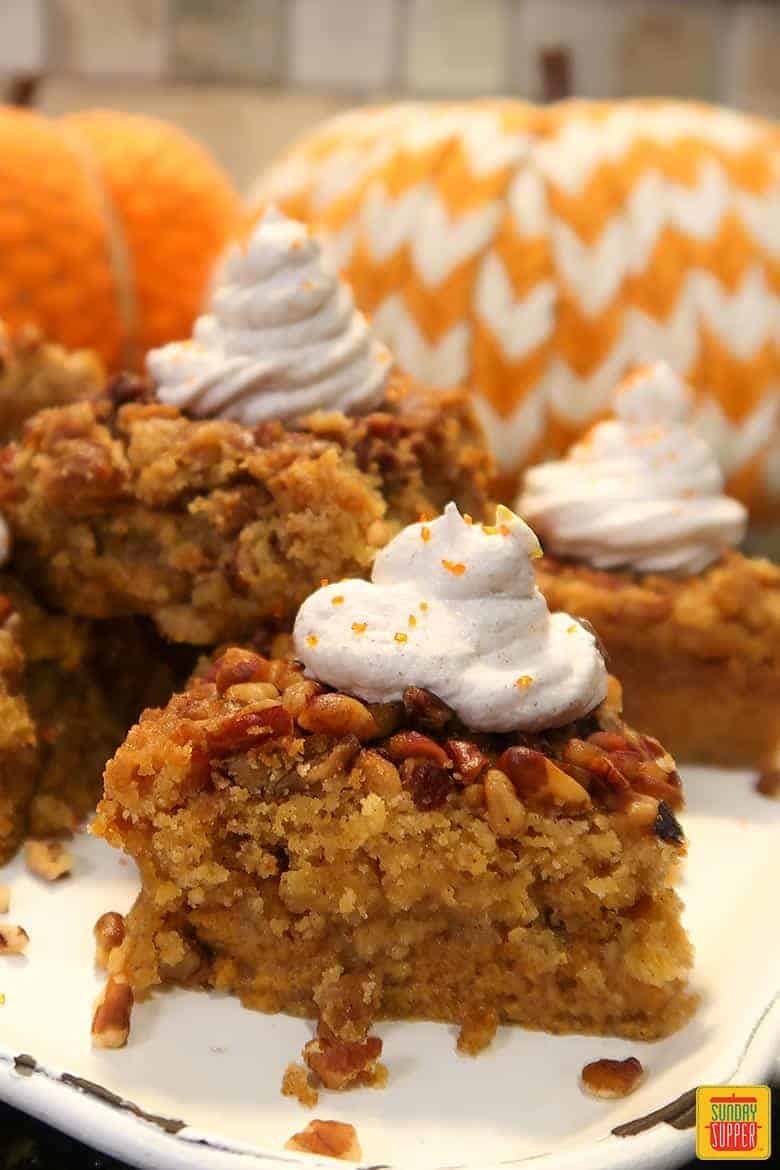 Pumpkin Crunch Cake on a white platter with whipped topping