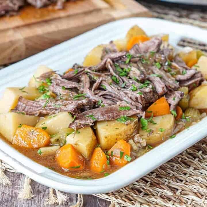 Slow cooker chuck roast with roast potatoes and carrots on a white platter
