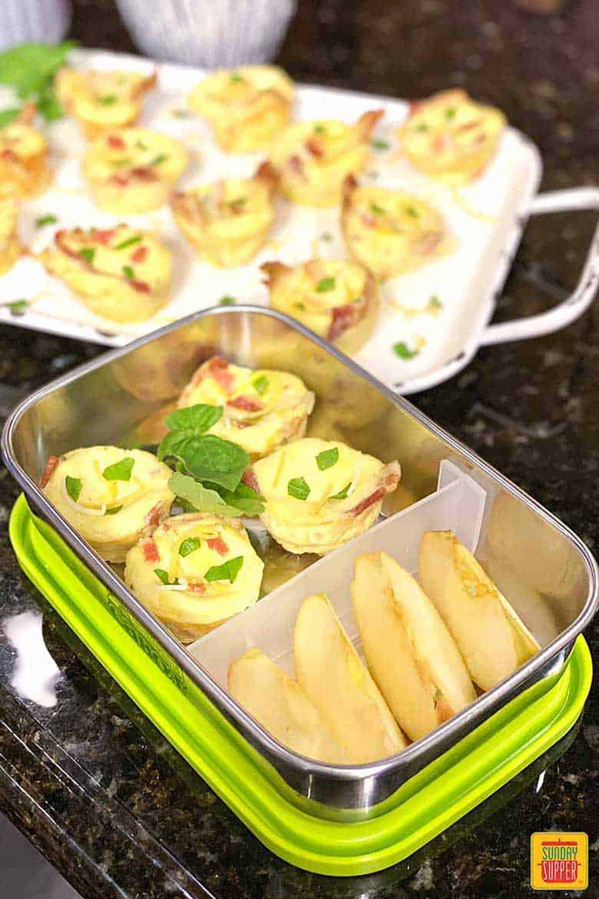 Starbucks egg bites in a bento box with apple slices for an on-the-go breakfast