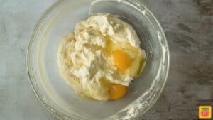 Adding eggs to the cheesecake mixture