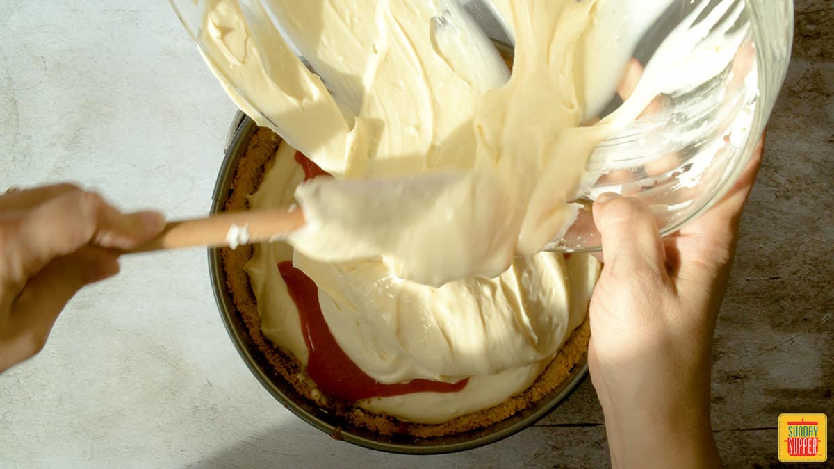 Pouring cheesecake mixture into a cake pan