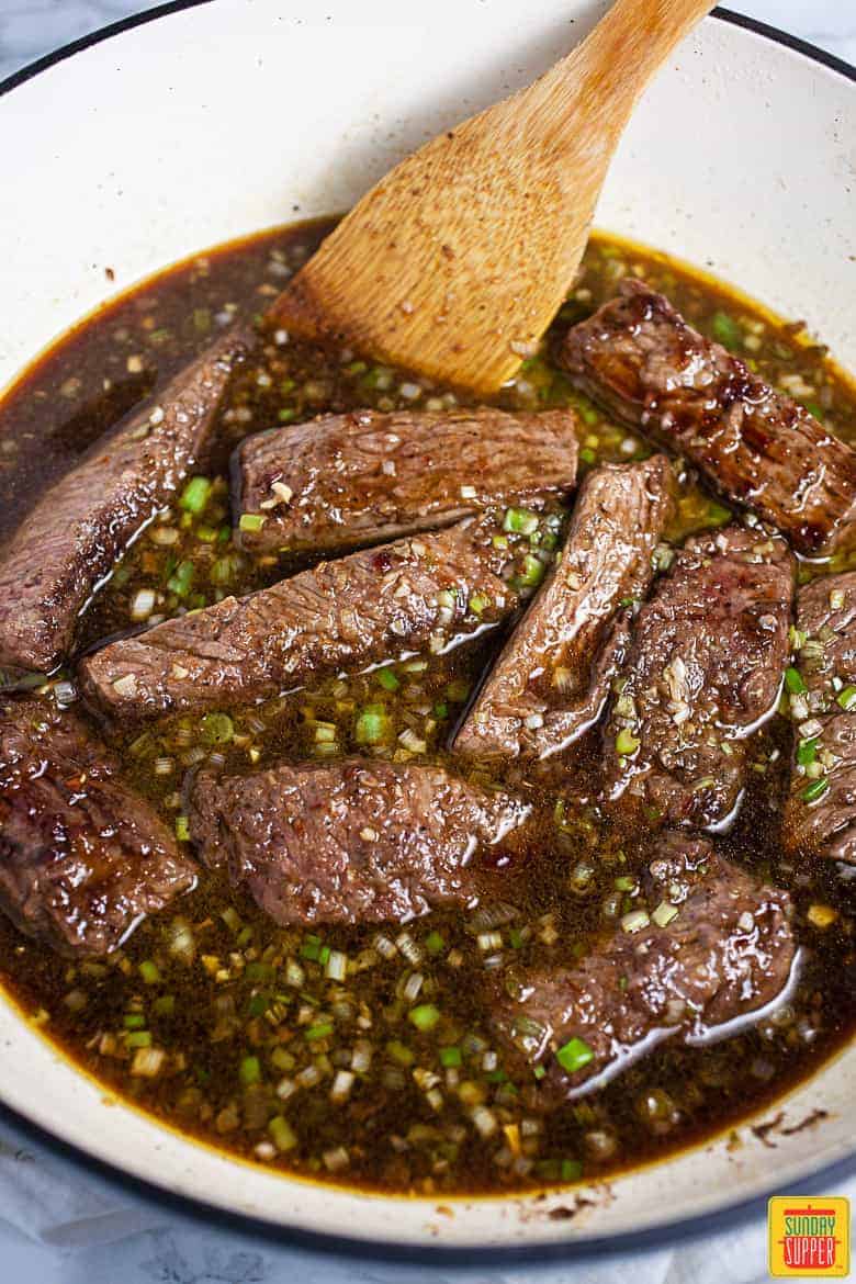 Beef short ribs covered in sauce in the Dutch Oven, ready to braise