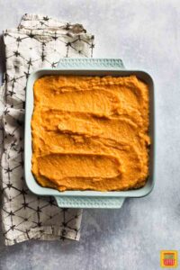 Mashed sweet potatoes spread in a square casserole dish