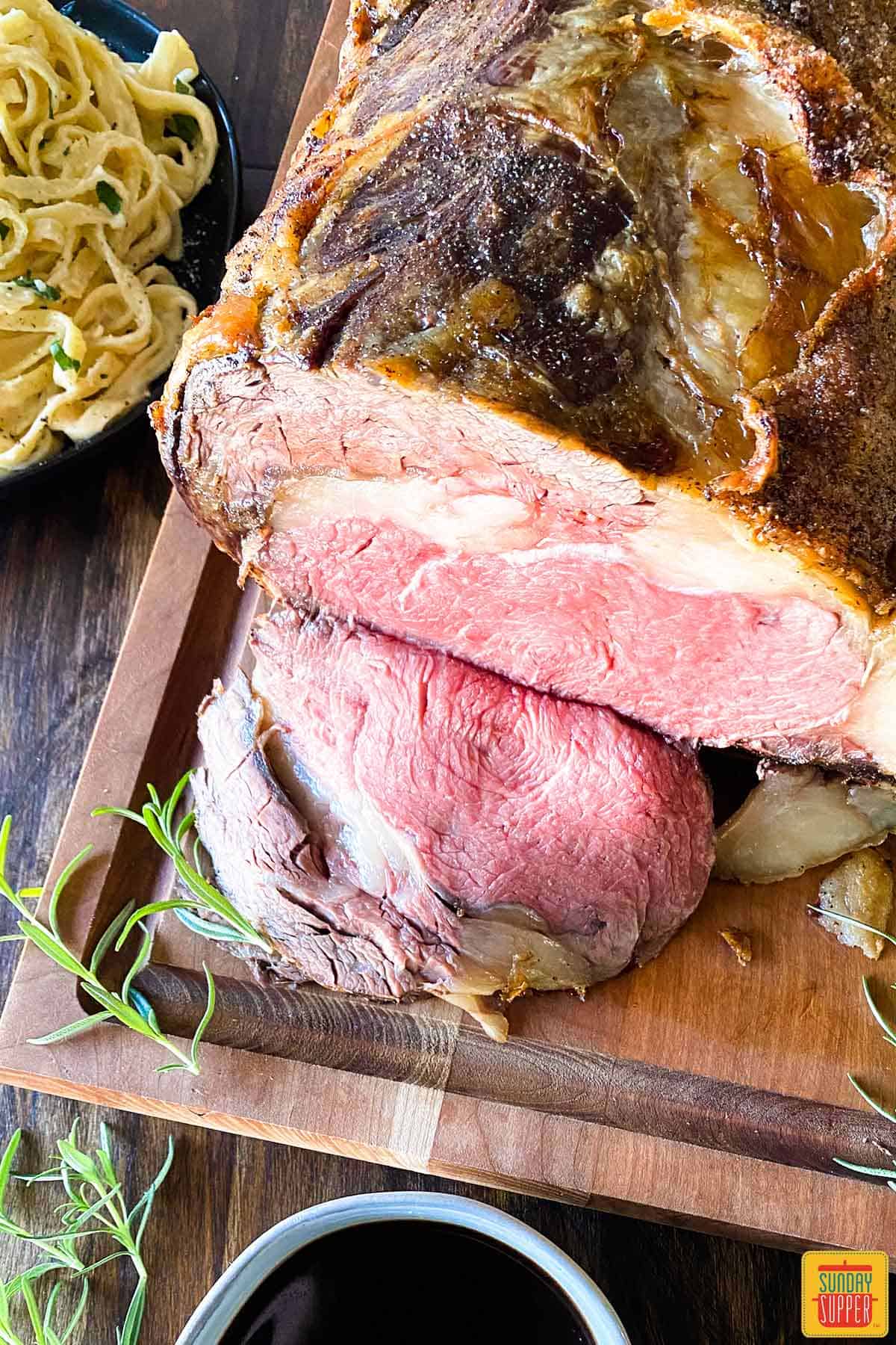 Slow roasted prime rib recipe next to pasta and a cup of au jus