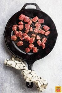 browning sides of sirloin steak bites in cast iron skillet