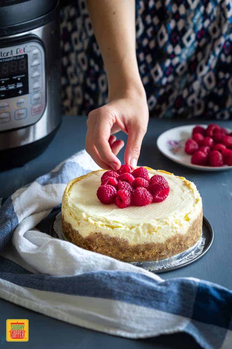 Topping the Instant Pot Cheesecake with raspberries