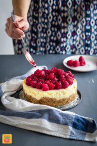 Instant Pot Cheesecake being decorated with raspberries and jam