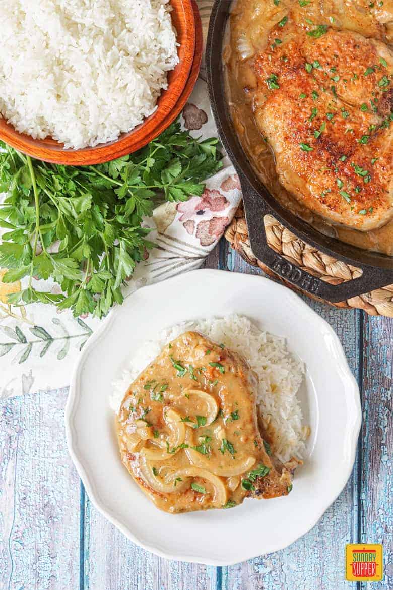 Southern Smothered Pork Chops with rice and gravy on a white plate