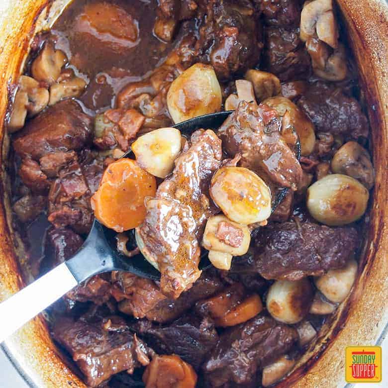 easy beef bourguignon recipe - spooning from dish