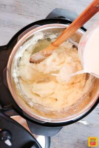 Gradually adding milk and seasoning to the mashed potatoes