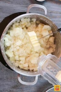Adding butter to potatoes in a pot