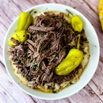 Mississippi pot roast on a white plate with pepperoncini peppers