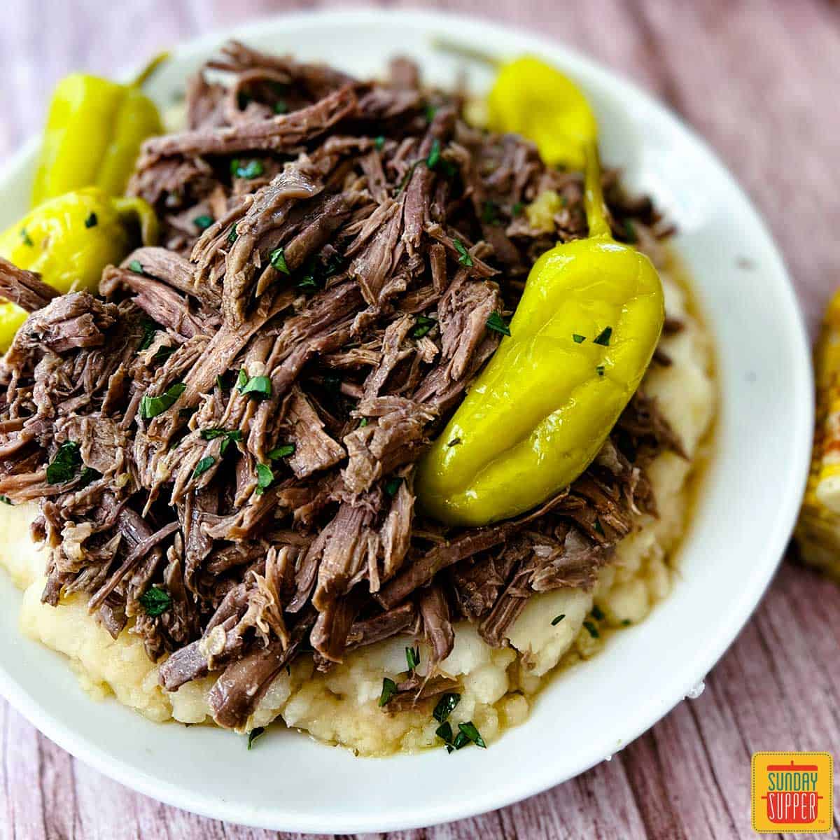 Mississippi pot roast on a white plate with pepperoncini peppers