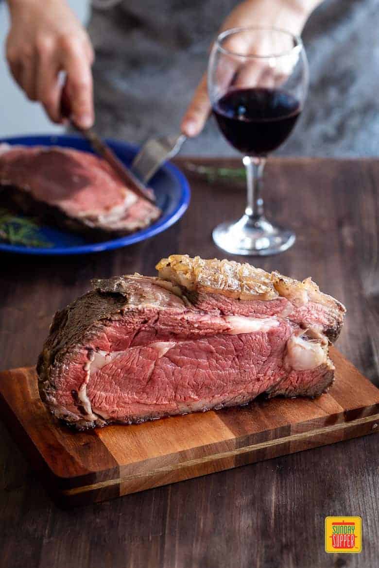 reverse sear prime rib on a cutting board with a glass of red wine