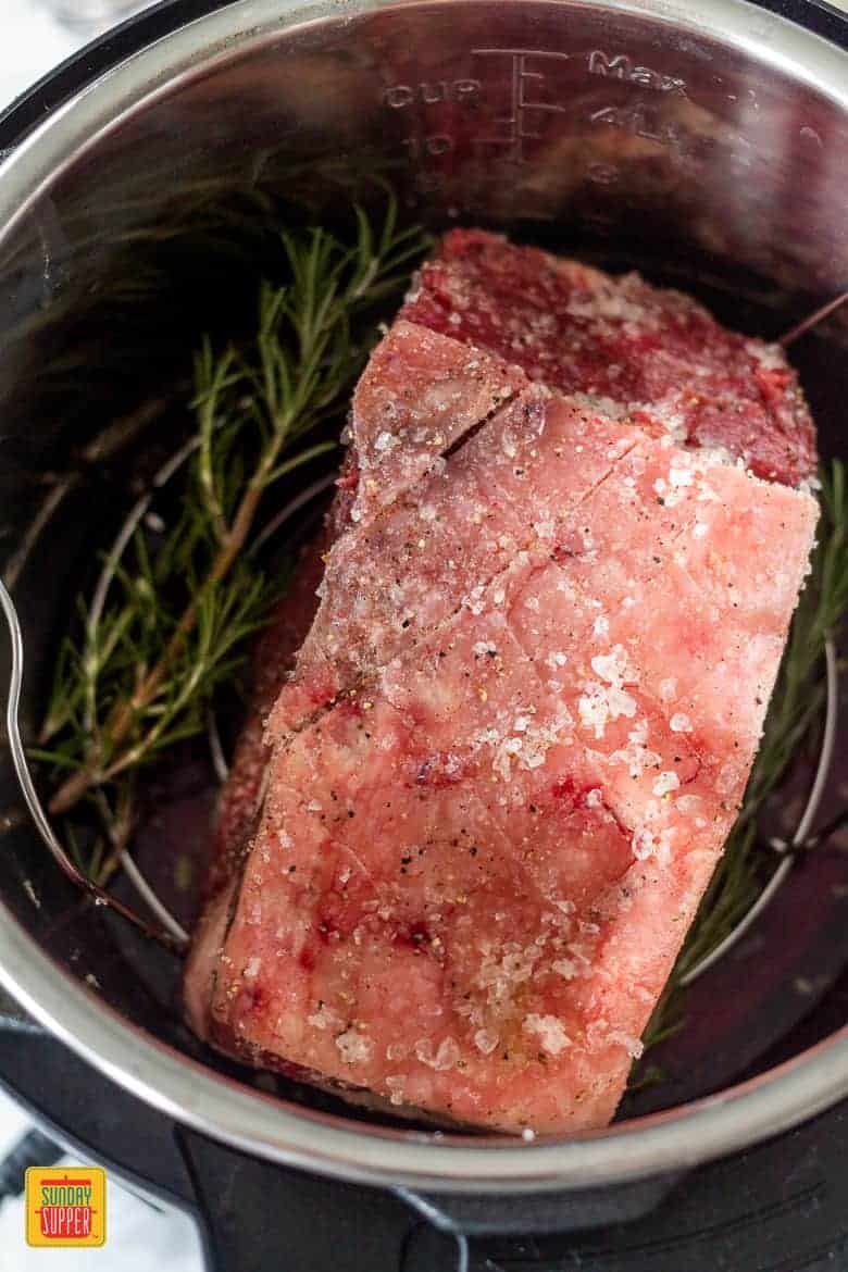 prime rib roast with sprigs of fresh herbs in the instant pot