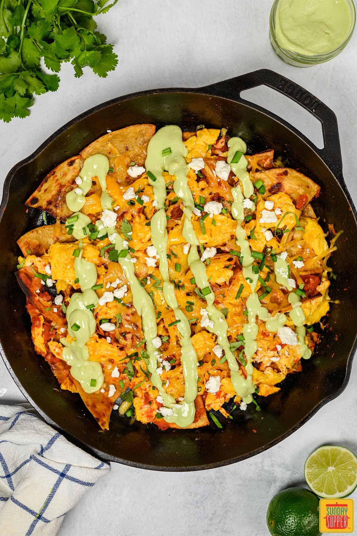 Chilaquiles in a cast iron skillet topped with avocado crema