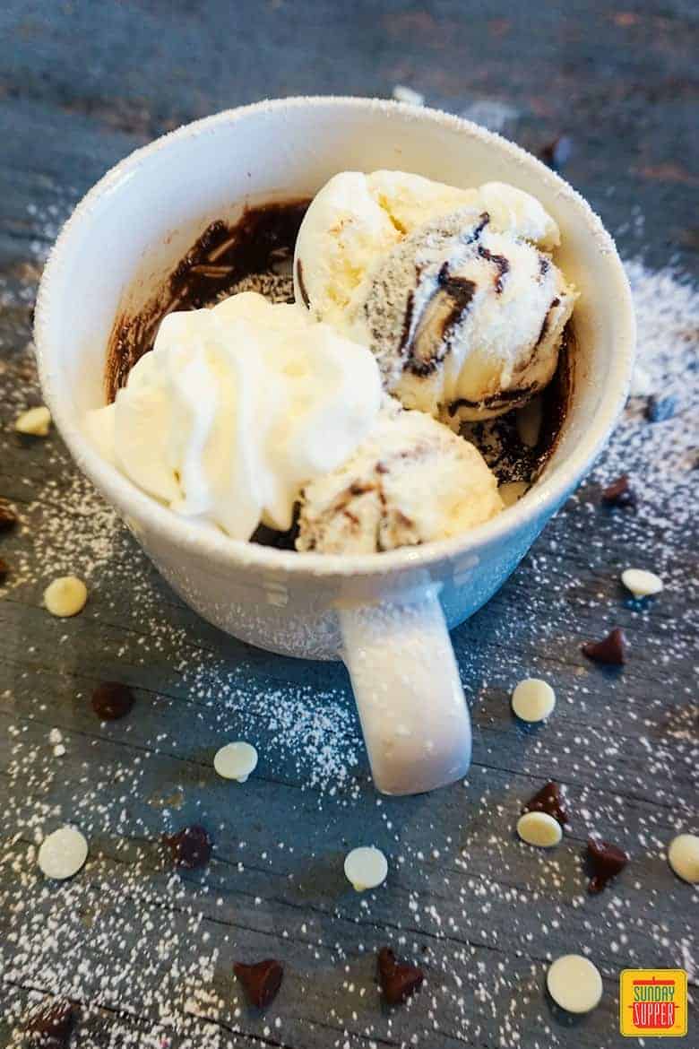 Gooey chocolate mug cake recipe in a white mug with ice cream and whipped cream