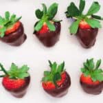 How to Make Chocolate Covered Strawberries: Six chocolate dipped strawberries in a row of three each on parchment paper