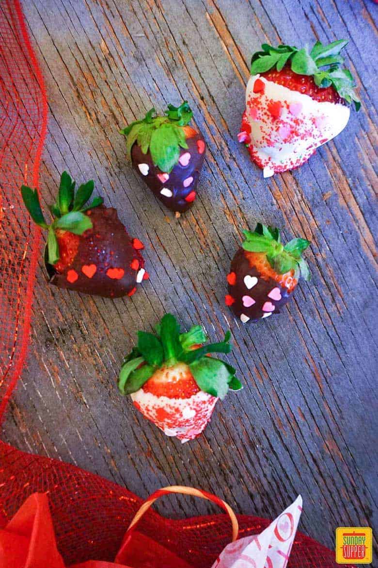 Five chocolate covered strawberries with heart sprinkles