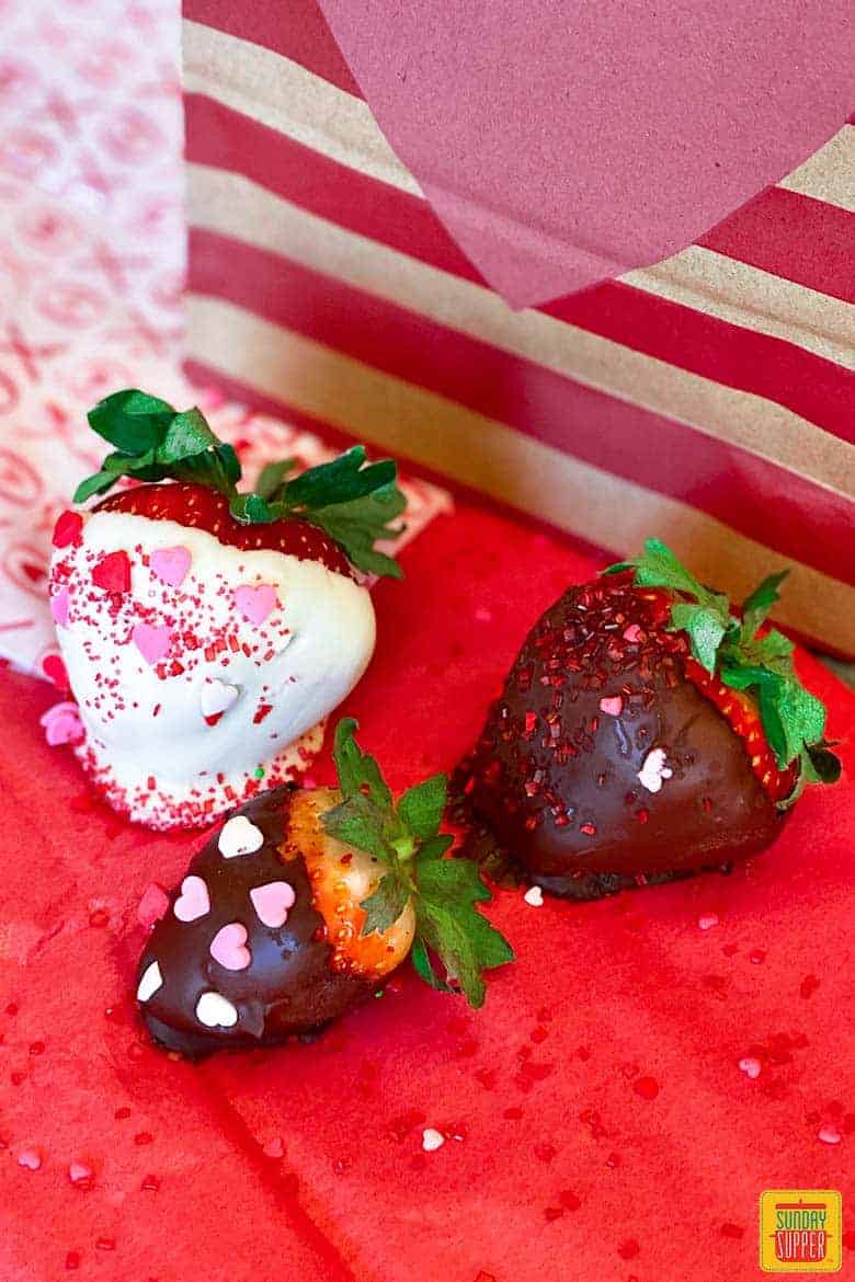 Three chocolate covered strawberries with heart sprinkles