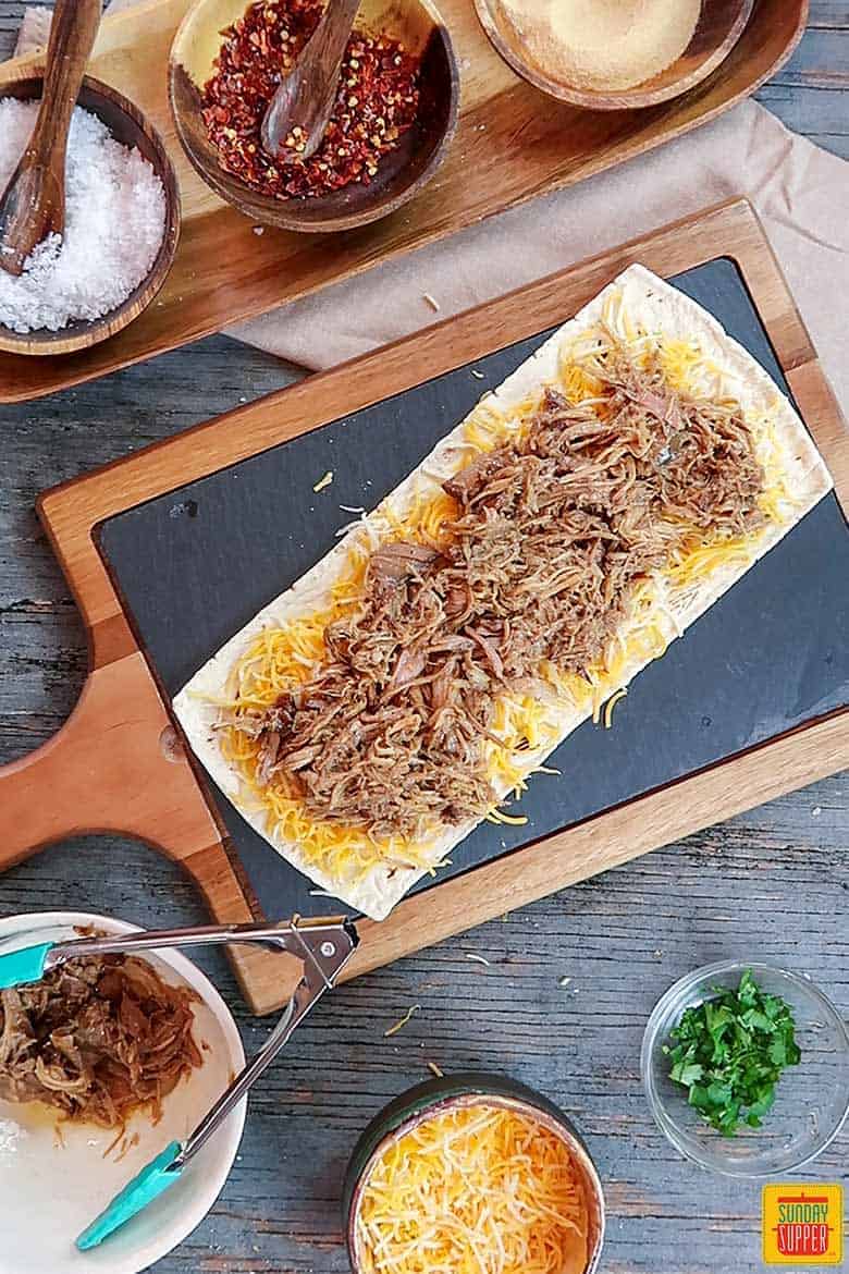Layer of pulled pork over cheese on flatbread