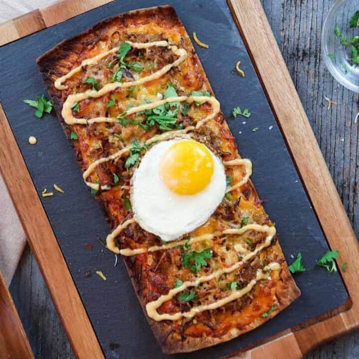 Pulled pork pizza flatbread recipe on serving board with fried egg on top