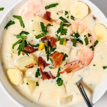 New England Seafood Chowder in a bowl with bacon and shrimp on top