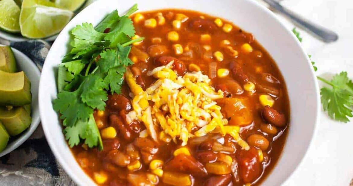 Slow cooker vegetarian chili in a white bowl with cilantro and cheese