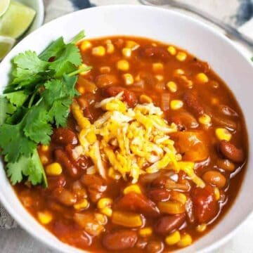 Slow cooker vegetarian chili in a white bowl with cilantro and cheese