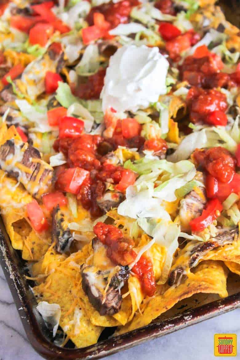 Nachos with steak tomato and lettuce in a sheet pan