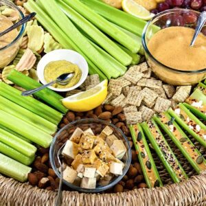 Close up of charcuterie board with celery sticks and dips in bowls