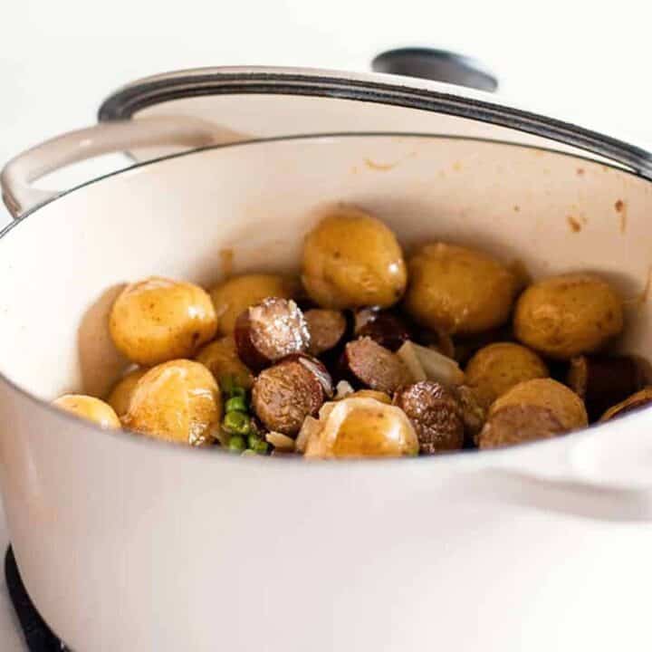 Smothered potatoes and sausage in a white Dutch oven
