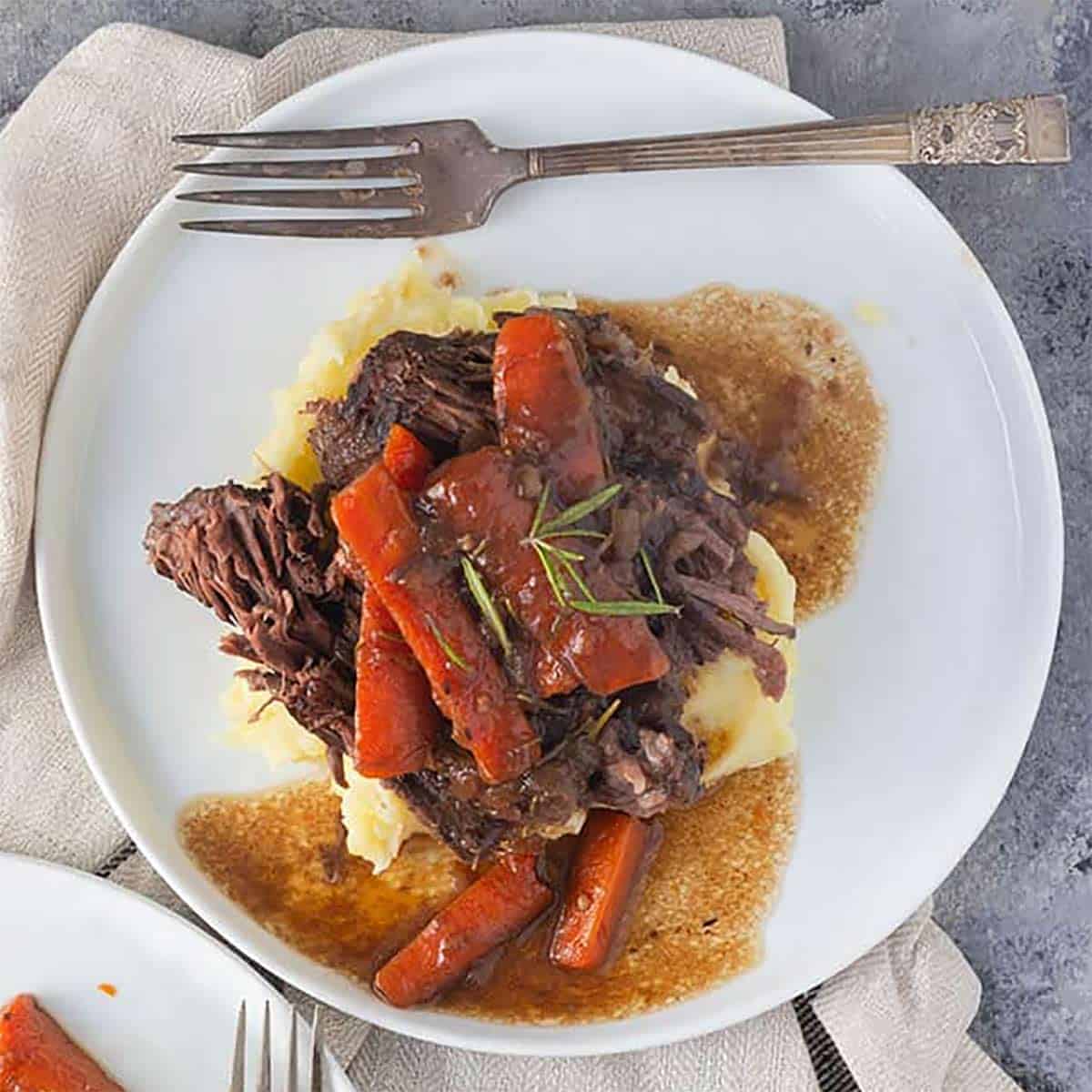 Dutch oven pot roast on a white plate with a fork