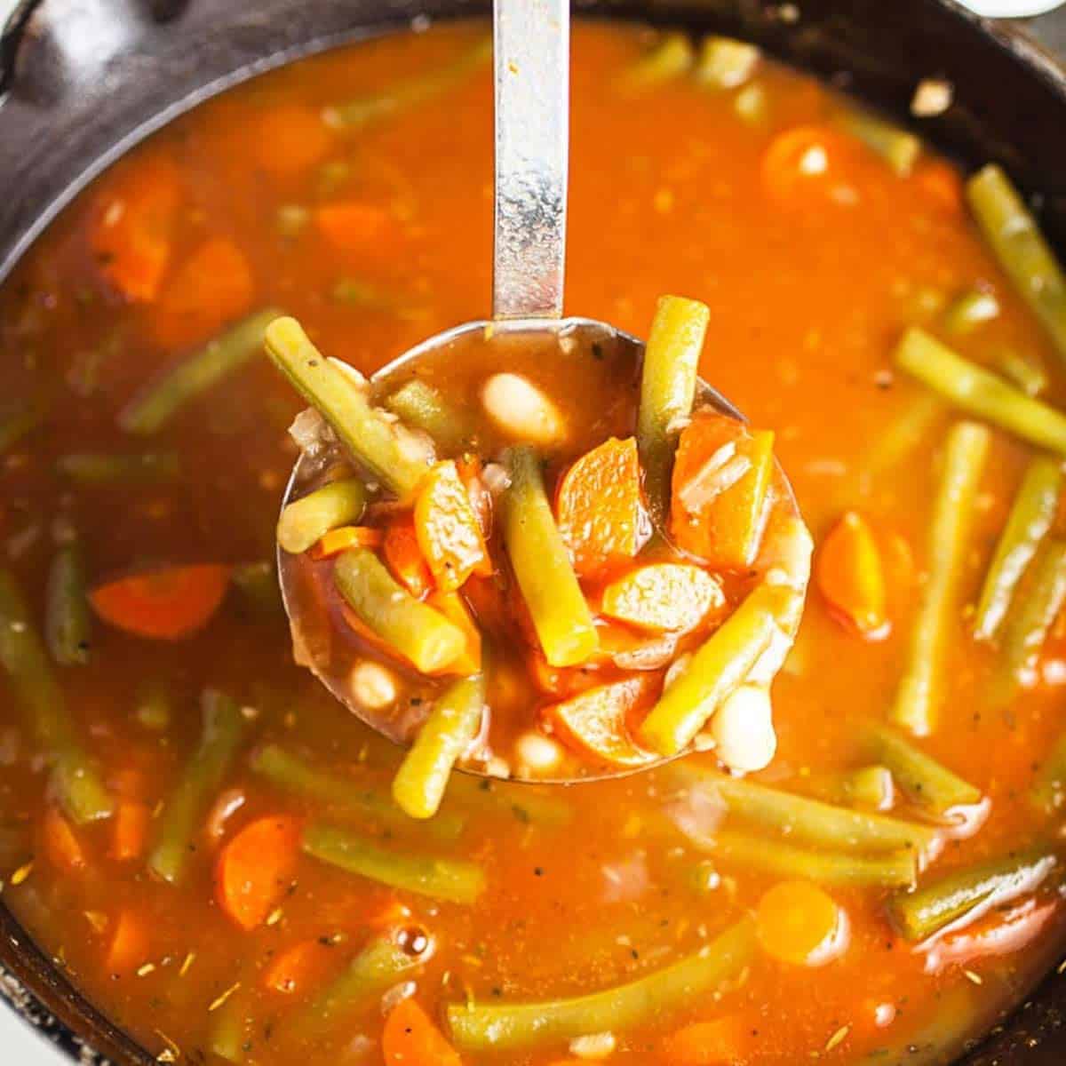 Ladle-full of Italian vegetable soup in the pot