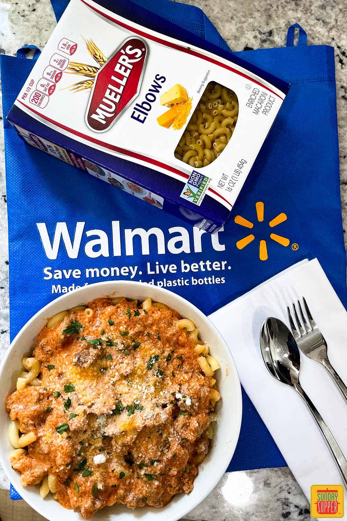 Pink pasta in a bowl with a Walmart bag and Mueller's pasta in a box