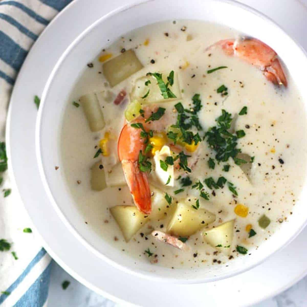 New England Seafood Chowder in a white bowl on a white plate