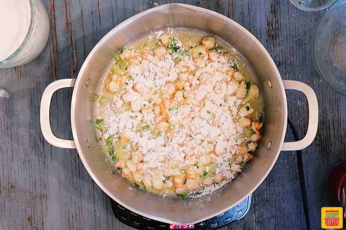 Adding flour to shrimp bisque in pot