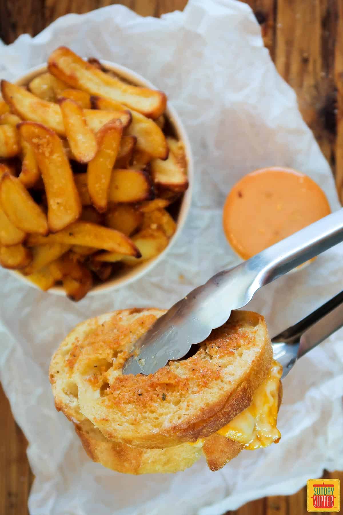 Holding an air fryer grilled cheese with tongs