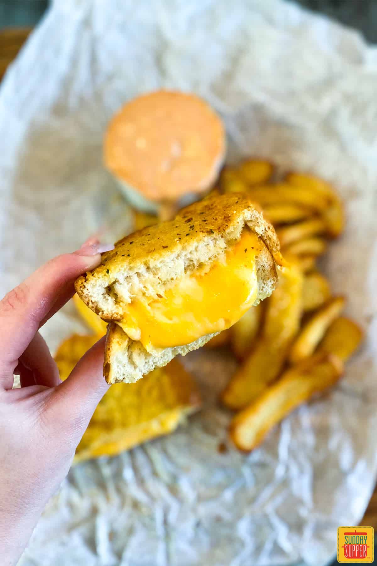 Holding half of a grilled cheese sandwich with gooey cheese