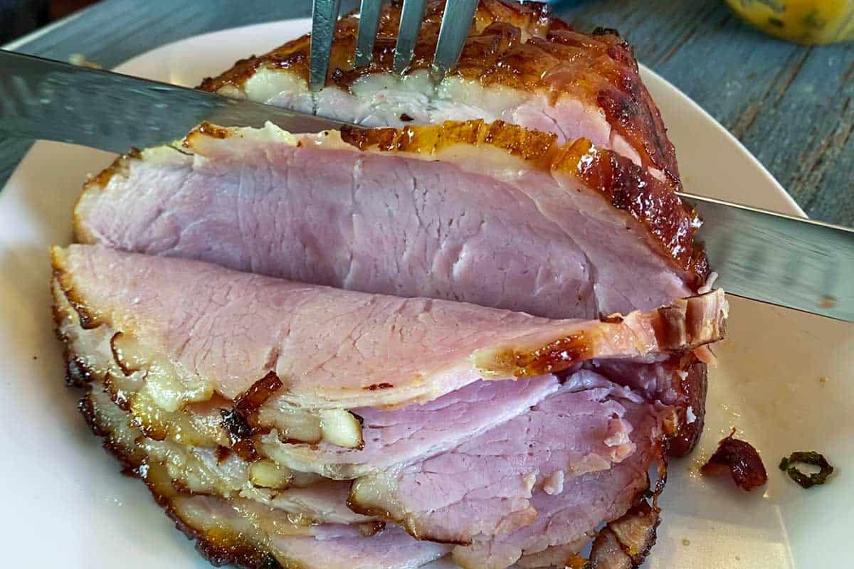 Cutting into an air fryer ham with a fork and knife