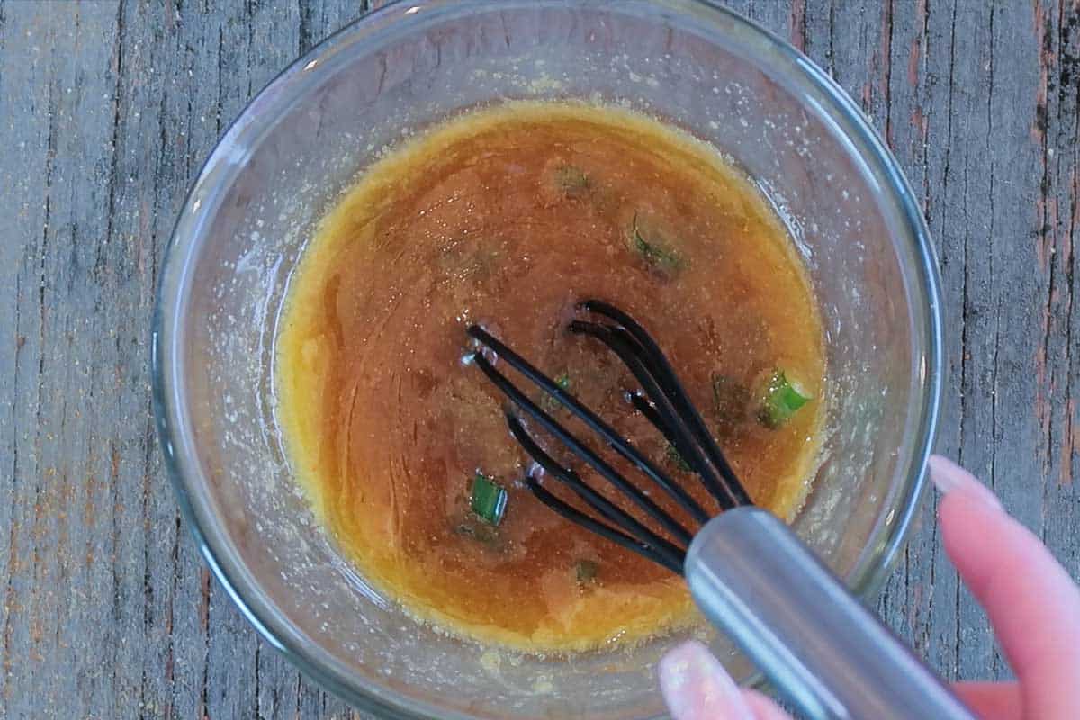Mixing honey ham glaze together with whisk in a glass bowl