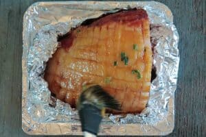Brushing honey ham glaze on ham
