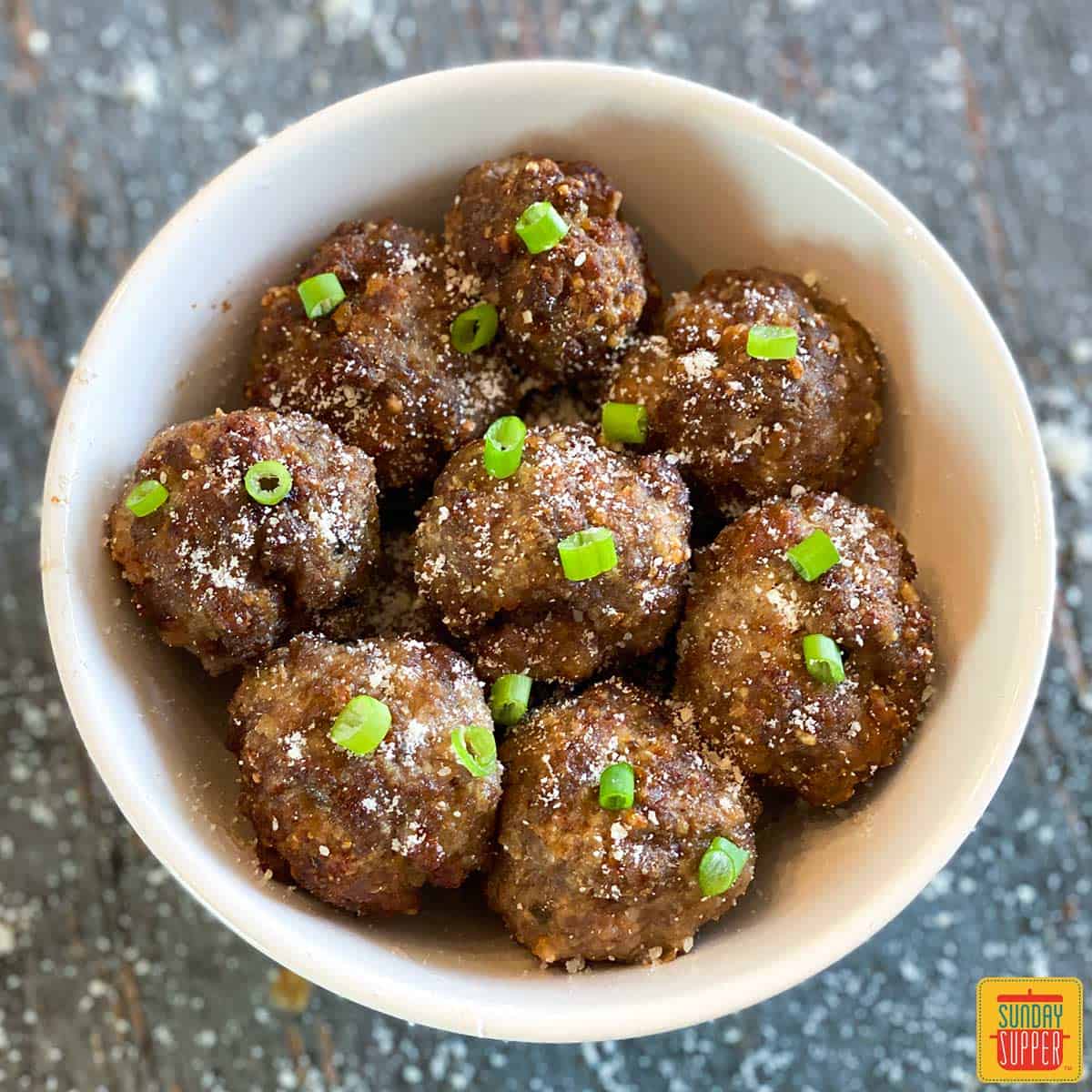 Close up of air fryer meatballs with green onions in a white bowl