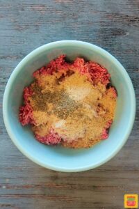Dry spices on top of meatball mixture in bowl