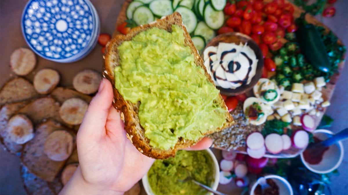 Holding a piece of toast with avocado spread