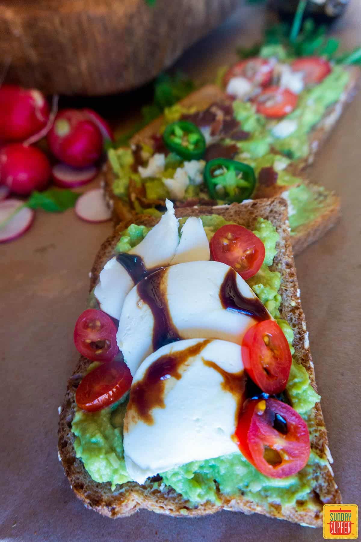 Close up of avocado toast with mozzarella, balsamic glaze, and tomatoes