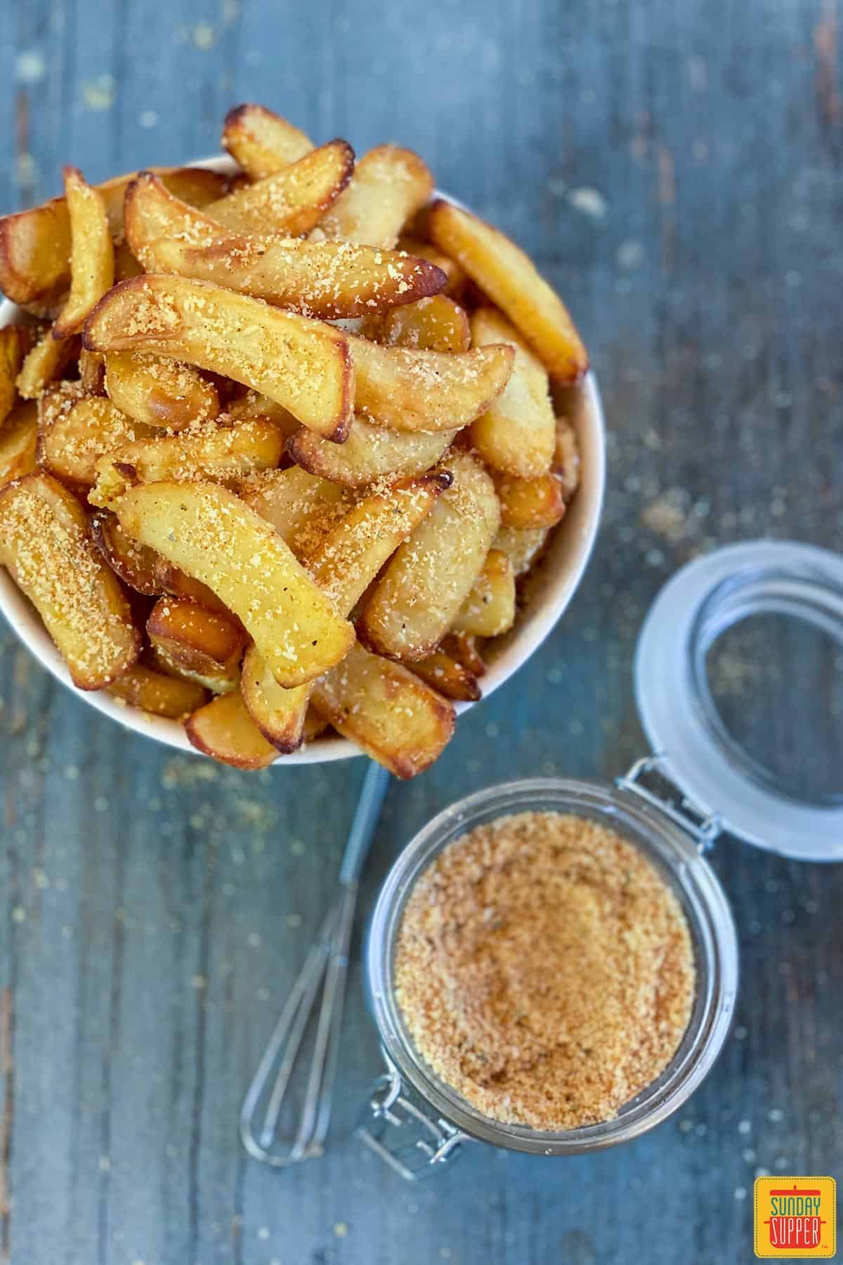 Best fry seasoning recipe in a jar near air fryer fries in a bowl