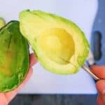 Half of an avocado cut into slices in a spoon