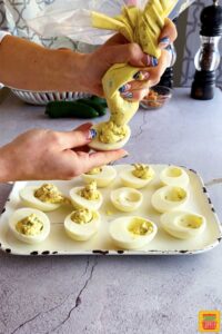 piping deviled eggs mixture into egg whites