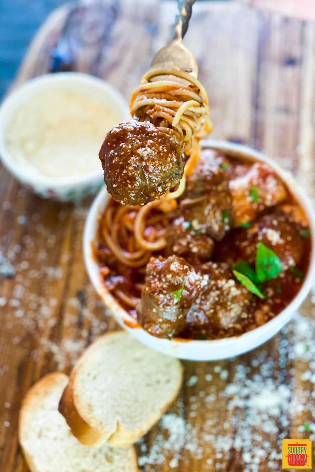 Lifting a meatball out of meatball sauce recipe with a fork